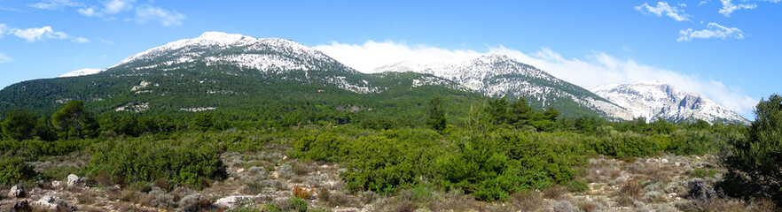 Winter photo of mount Parnitha covered with slight snow and deep blue cloudy sky on a sunny morning