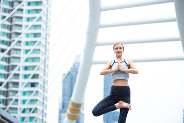 Fototapeta na wymiar Caucasian woman wearing sportswear practicing yoga in the city