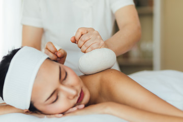 Obraz na płótnie Canvas Massage, Spa, Health & Wellness Retreats concept. Close up Herbal Ball for Thailand Traditional massage and spa. Young beautiful asian woman in spa and massage environment