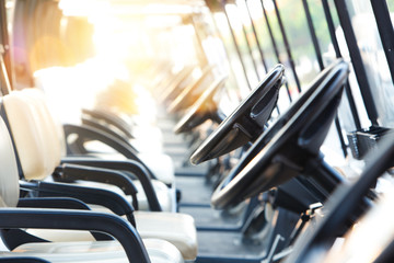 Golf cars or golf carts in a row outdoors on a sunny spring day