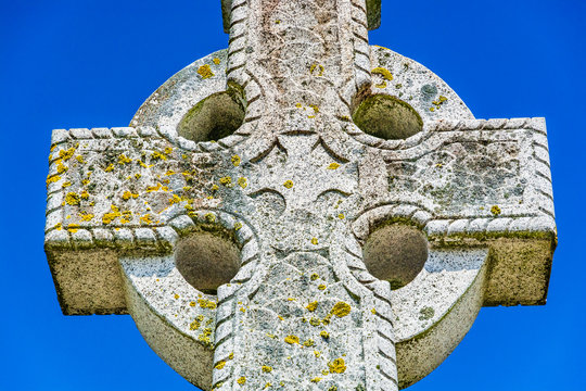 Old stone celtic cross on a bright clear blue sky background