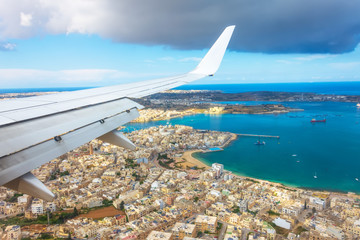 View from the porthole of a passenger plane on the coast of Malta with typical houses.
