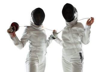 Confidence. Teen girls in fencing costumes with swords in hands on white background. Young female...