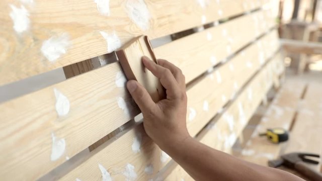Man sanding wood to refinish with paint in carpentry shop,  Man hand and sandpaper.
