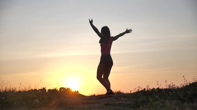 Happy woman jumping on beach enjoying sunset on summer travel vacation holiday. Happiness and bliss concept video with female jumping of joy celebrating in silhouette. SLOW MOTION 4k