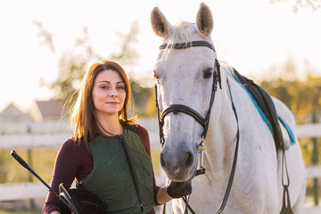 Obraz premium The owner and his white horse are preparing to ride.