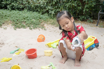 Asian baby girl playing sand outdoor. Kid building sand castle.