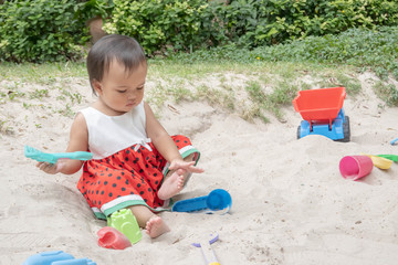 Asian baby girl playing sand outdoor. Kid building sand castle.