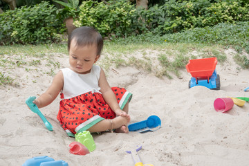 Asian baby girl playing sand outdoor. Kid building sand castle.
