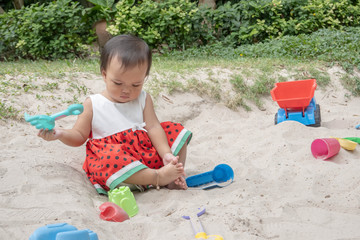 Asian baby girl playing sand outdoor. Kid building sand castle.