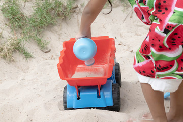Asian baby girl playing sand outdoor. Kid building sand castle.