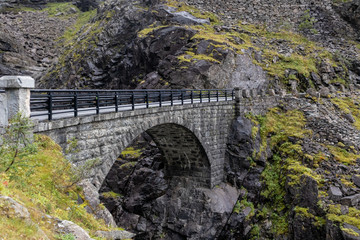 Fototapeta na wymiar Stone bridge and waterfall on Trolls Path Trollstigen or Trollstigveien scenic mountain road in Norway Europe. Tourist route.