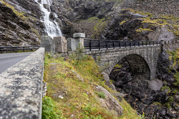 Stone bridge and waterfall on Trolls Path Trollstigen or Trollstigveien scenic mountain road in...