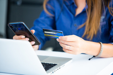 online shopping concepts. Woman hand  holding mobile phone and credit card with Payment Detail page display. using smartphone and laptop computer for online shopping