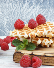 A stack of sweet baked waffles and large raspberries