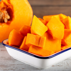 Peeled and chopped pumpkin on wooden background.