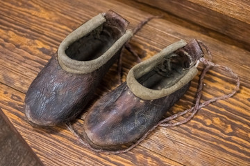 first Slavic shoes made from pieces of soft leather. Old homemade shoes on a wooden floor