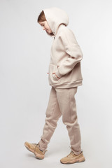 Young girl wearing blank and oversize beige long hoody, beige pants, beige sneakers . Standing. Isolated on white background.