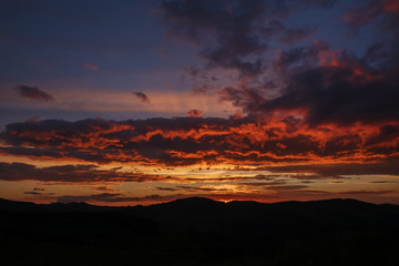 Red light after sunset, deep blue color of the sky. The rays of the setting sun illuminate the clouds below.