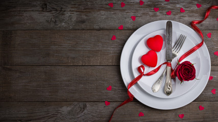 Valentine's day dinner concept, flat white plate, fork, knife and two red heart
