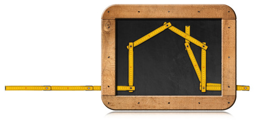 Yellow wooden folding ruler in the shape of a house in a blackboard with copy space. Isolated on...