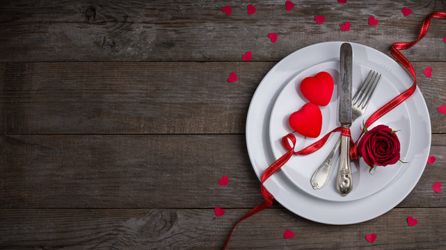 Valentine's day dinner concept, flat white plate, fork, knife and two red heart