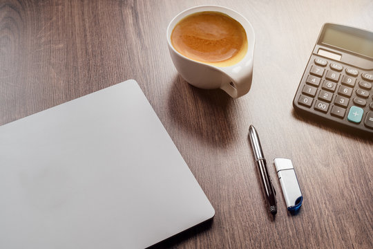  Laptop auf einem Schreibtisch mit einem Taschenrechner, Kugelschreiber und einer Kaffeetasse