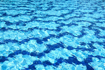 The water surface of the swimming pool turquoise color, illuminated by the sun