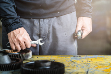 Mechanic man hold engine gear on the table, mechanical maintenance and repair background