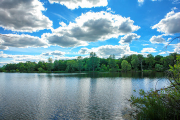 The blue sky with the clouds above the clear blue lake
