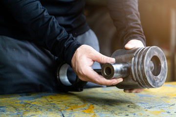 Mechanic man trying to assembly piston set of diesel engine,  mechanical maintenance and repair background