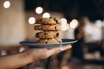 Pile of golden brown homemade oatmeal cookies on dark table background. High tower of tasty peanut oatcakes, healthy sweet home-baked products, selective focus, copy space
