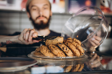 the seller in the bakery packs the customer's order, receives with a smile the cookie chosen by the...