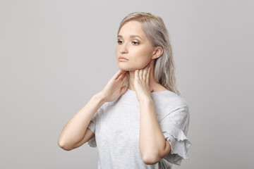 Female checking thyroid gland by herself. Close up of woman in white t- shirt touching neck with red spot. Thyroid disorder includes goiter, hyperthyroid, hypothyroid, tumor or cancer Health care.