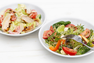 white deep plates with fresh salad ingredients mixed with sauce placed on an attractive background. A place for a menu, banner or advertisement