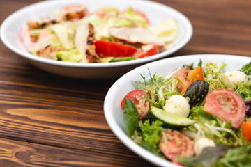 white deep plates with fresh salad ingredients mixed with sauce placed on an attractive background. A place for a menu, banner or advertisement