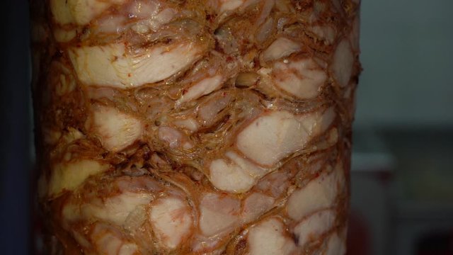 Closeup view of cooking tasty spicy juicy chicken meat spinning around at special rotisserie. Preparing meat for traditional turkish kebab. Slow motion full hd video footage.
