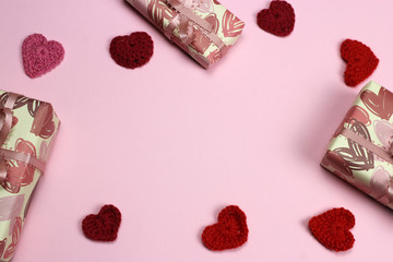 Frame of knitted hearts and gifts on a pink background. Space for text. Valentine's day, love and wedding concept