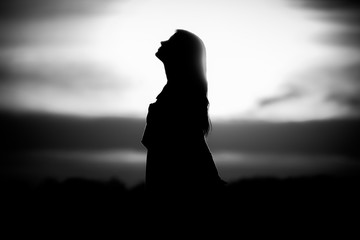 Youth woman soul at white sun meditation dreaming past times. Silhouette in front of sunset or...