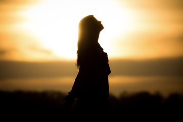 Youth woman soul at orange sun meditation awaiting future times. Silhouette in front of sunset or sunrise in summer nature. Symbol for healing burnout therapy, wellness relaxation or resurrection - obrazy, fototapety, plakaty