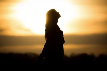 Vlies Fototapete Seoel Youth woman soul at orange sun meditation awaiting future times. Silhouette in front of sunset or sunrise in summer nature. Symbol for healing burnout therapy, wellness relaxation or resurrection