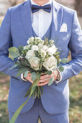 Wedding decor. Groom with bouquet in his hands. Young elegant stylish man dressed in modern formal clothes