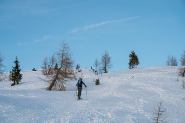 Lonely skiier ascending snowy mountain top at dusk.
