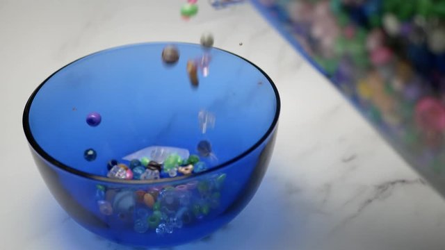 Assorted Beads Pour Into Blue Glass Container