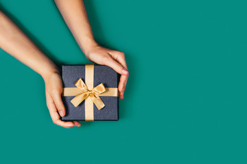 Gift box with surprise in a female hands on green background. Flat lay, top view, place for text.