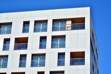 Obraz premium Contemporary residential building exterior in the daylight. Modern apartment buildings on a sunny day with a blue sky. Facade of a modern apartment building