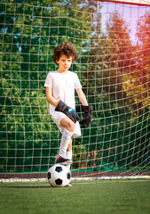 Summer soccer tournament for young kids. football club. emotions and joy of the game. Young goalie. Kids - soccer champion. Boy goalkeeper in football sportswear on stadium with ball. Sport concept.