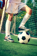 Soccer, football kick off. Man controls a soccer ball on the grass. Summer soccer tournament for young kids. Boy goalkeeper in football sportswear on stadium with ball. Sport concept.