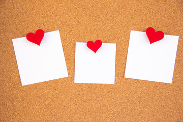 three red heart note paper on cork board