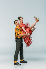 cheerful dancer holding partner while dancing boogie-woogie on grey background